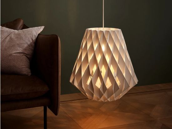 Ketra Pilke lighting fixture with warm, low lighting in a room with a brown chair and dark green walls. 